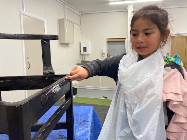 A tamariki paints a chair as part of the zero-waste project 