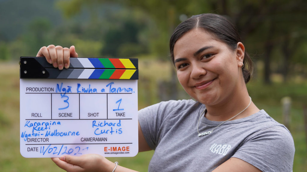 Keeti Slate in holds a clapper board at a Ngā Pakiaka rangatahi filmmaking event