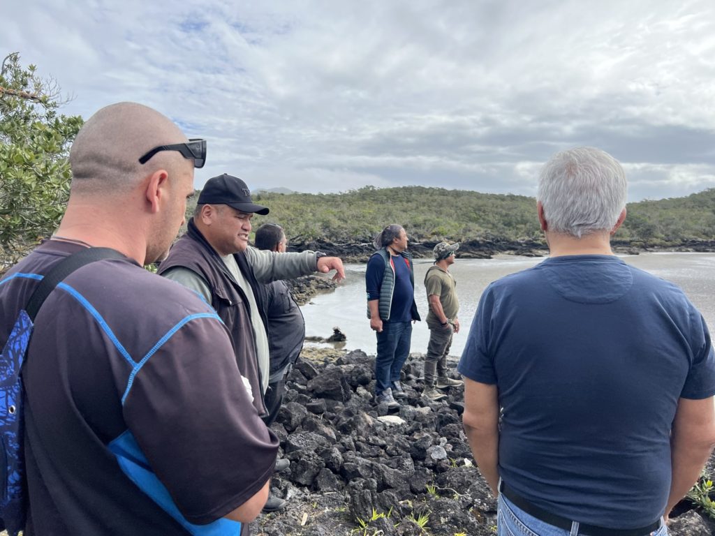 Mikaira and tāne take time to talk on the rocky shore of Rangitoto Island