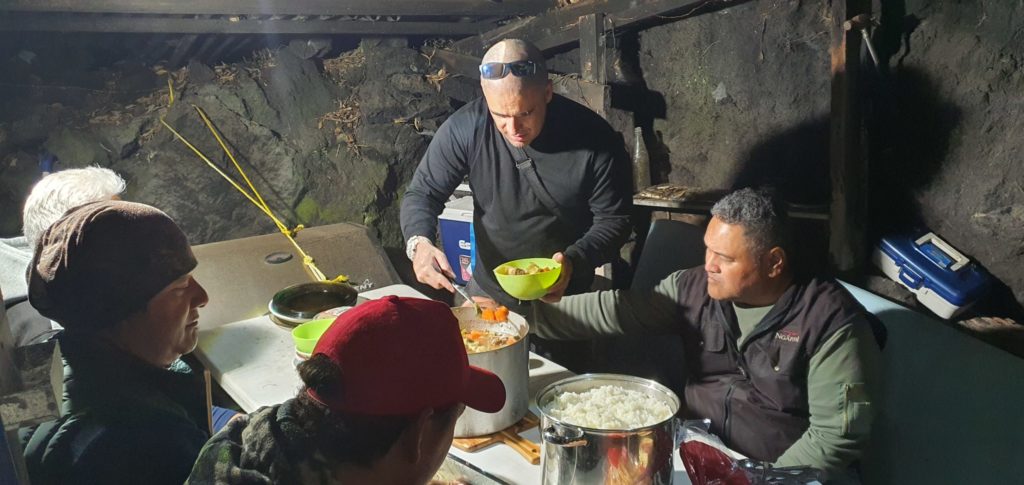 Mikaira and tāne share food at night on Rangitoto Island.