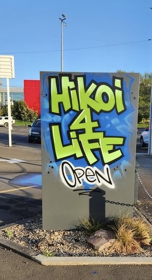A street sign in graffiti style saying "Hikoi4Life Open"