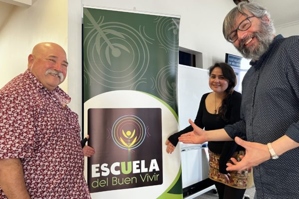 Three of the team working on the ALAC Wellbeing Toolkit happily show off a banner showing the logo and name of the programme, Escuela del Buen Vivir. On the left is Esteban Espinoza, ALAC Founder and Director, with specially trained ALAC Wellness Workers, Carolina Lagos in the center, and Jose Patricio Contreras on the right.