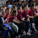 In this picture, primary aged school children watch one of the films in the E Tū Whānau Rangatahi Film Awards 2024. They're seated in a row. Some are smiling at what they are seeing.