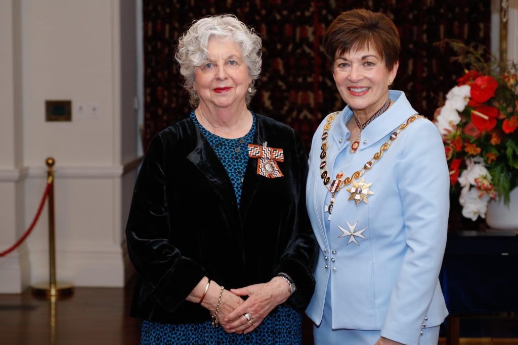 Margaret Western is pictured standing next to the Governor General, The Right Honourable Patsy Reedy who is wearing a golden star-shaped medal and elaborate decorative gold chain associated with her official position. Both women are dressed formally, with Margaret wearing some sort of bright red, white and black broach on the lapel of her black jacket.