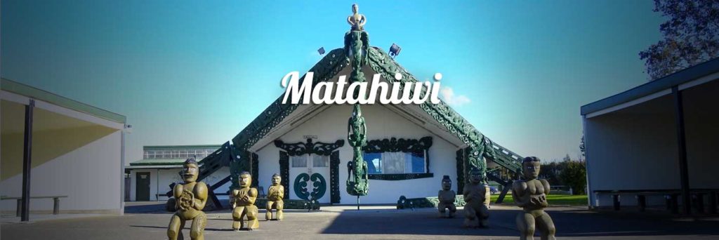 This image shows the whare nui of Matahiwi, one of the marae hosting the open days. The picture shows the wharenui in gentle sunlight. General marae grounds and buildings are visible next to the wharenui. 