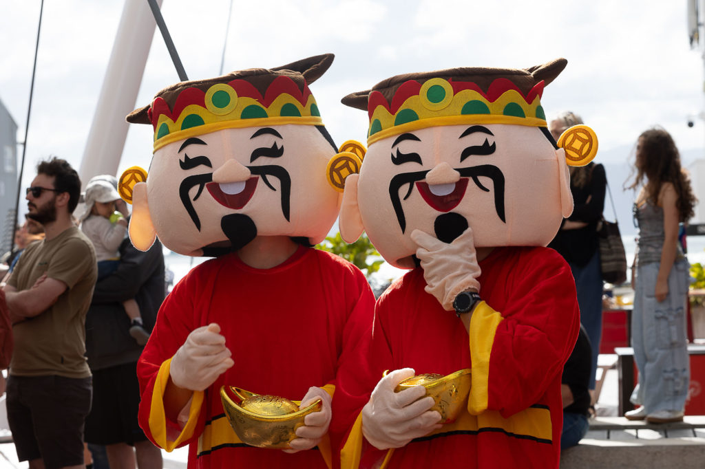 Two people dressed up as colourful Vietnamese cultural characters are depicted at a street festival for Lunar New Year.