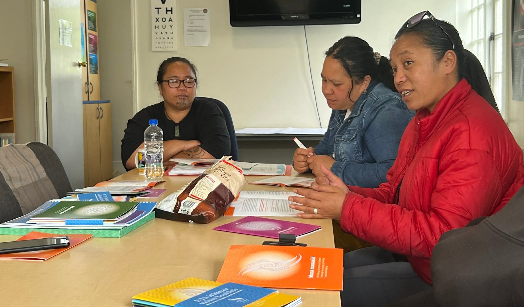 3 women are sitting around a table at a wananga