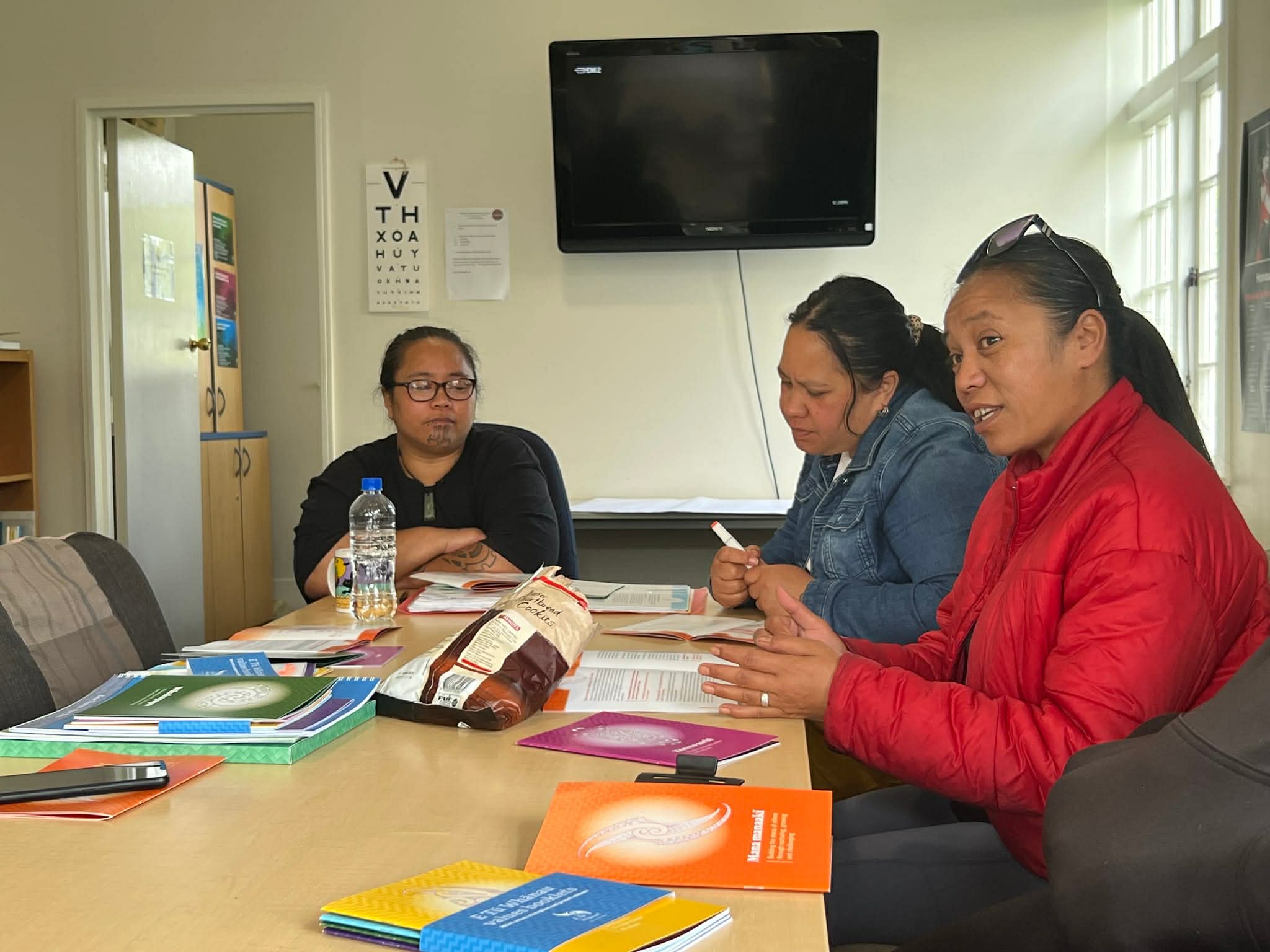 3 women are sitting around a table at a wananga