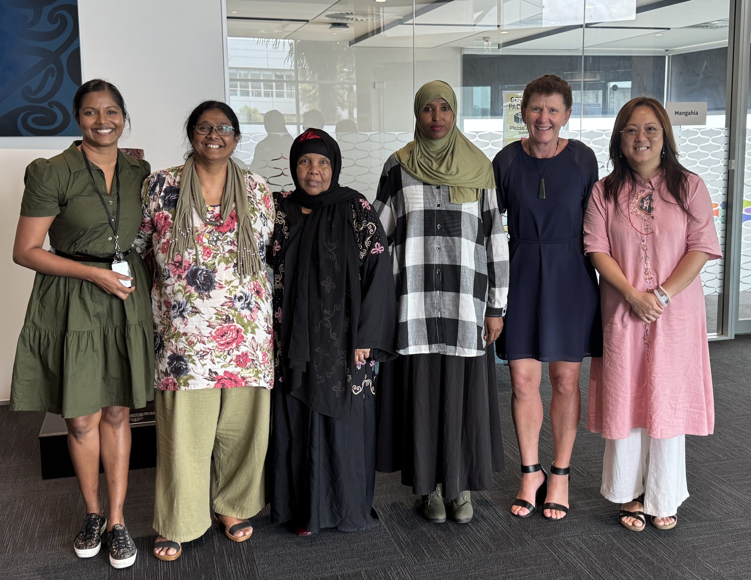 A group of women who worked together to support a sewing course stand together in a line
