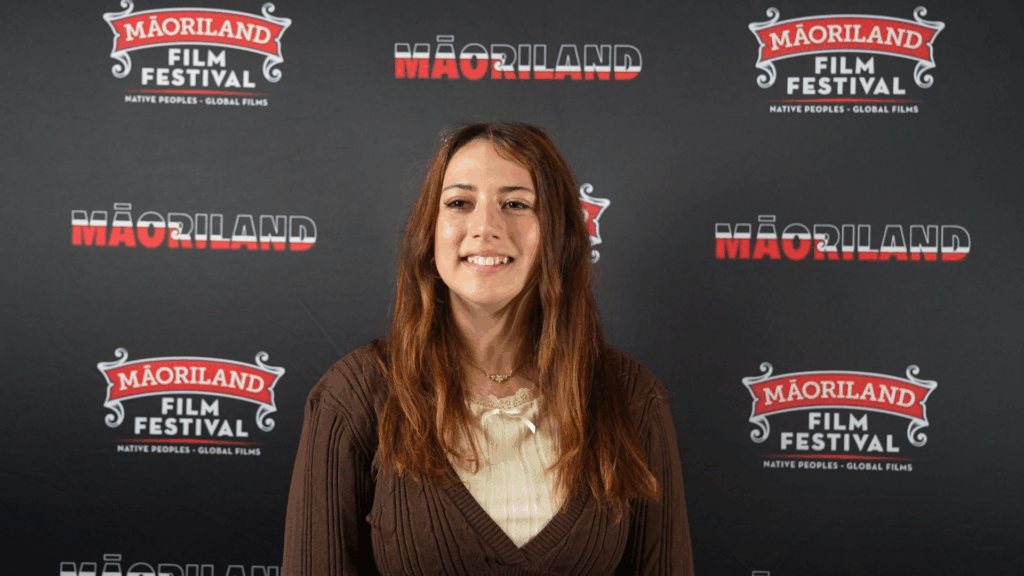 Lina Valu, a young woman with brown hair, smiles at the camera.