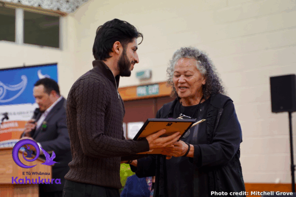 Zaki Ayubu receiving his Rangatahi Kahukura - Emerging Leader award from Katie Murray. They are both smiling .