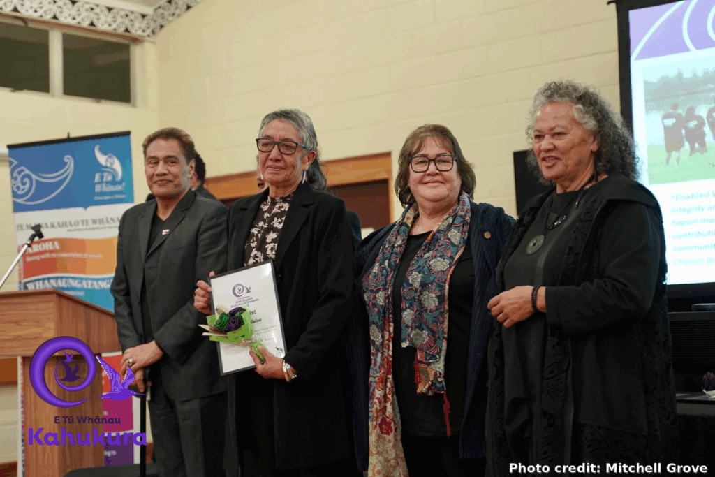 Darrin Haimona, Shelly Smith (CEO of Enabled Wairoa), Heni Turner (E Tū Whānau Kaiwhakahaere) and Katie Murray stand together at the E Tū Whānau Kahukura Awards 2026. Shelly holds flowers and a certificate.