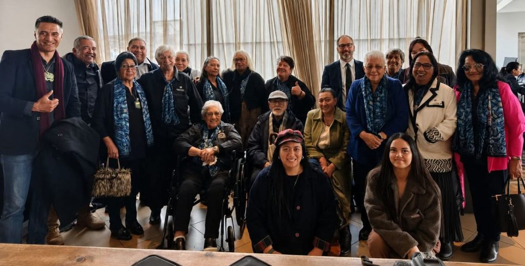 A group representing Nannies Against P are pictured. There are about 30 people pictured, some of whom are in wheelchairs. Everyone is dressed formally.