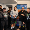 A group of Tsix e Whānau Rangimarie kaimahi are pictured together in front of a banner of the six E Tū Whānau values