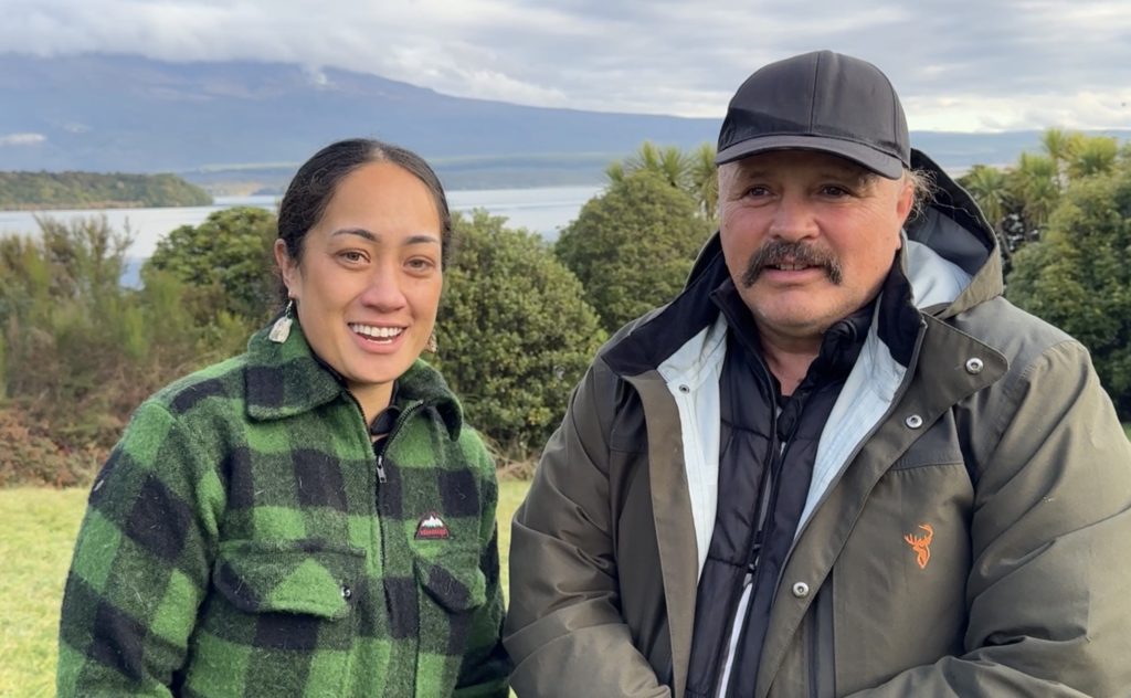 Tiara and Matthew - two Atamai Ora wānanga participants - are pictured smiling and standing together outdoors. Behind them, a large body of water and the lower slopes of Tongariro maunga are visible.